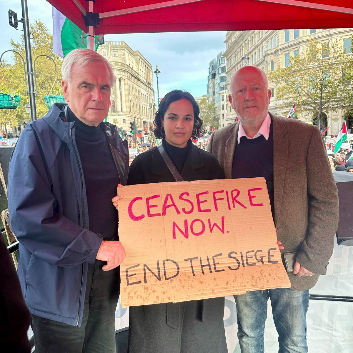 Nadia with John McDonnell MP and Andy McDonald MP at the national Palestine demonstration, holding a sign that read "Ceasefire now. End the siege."
