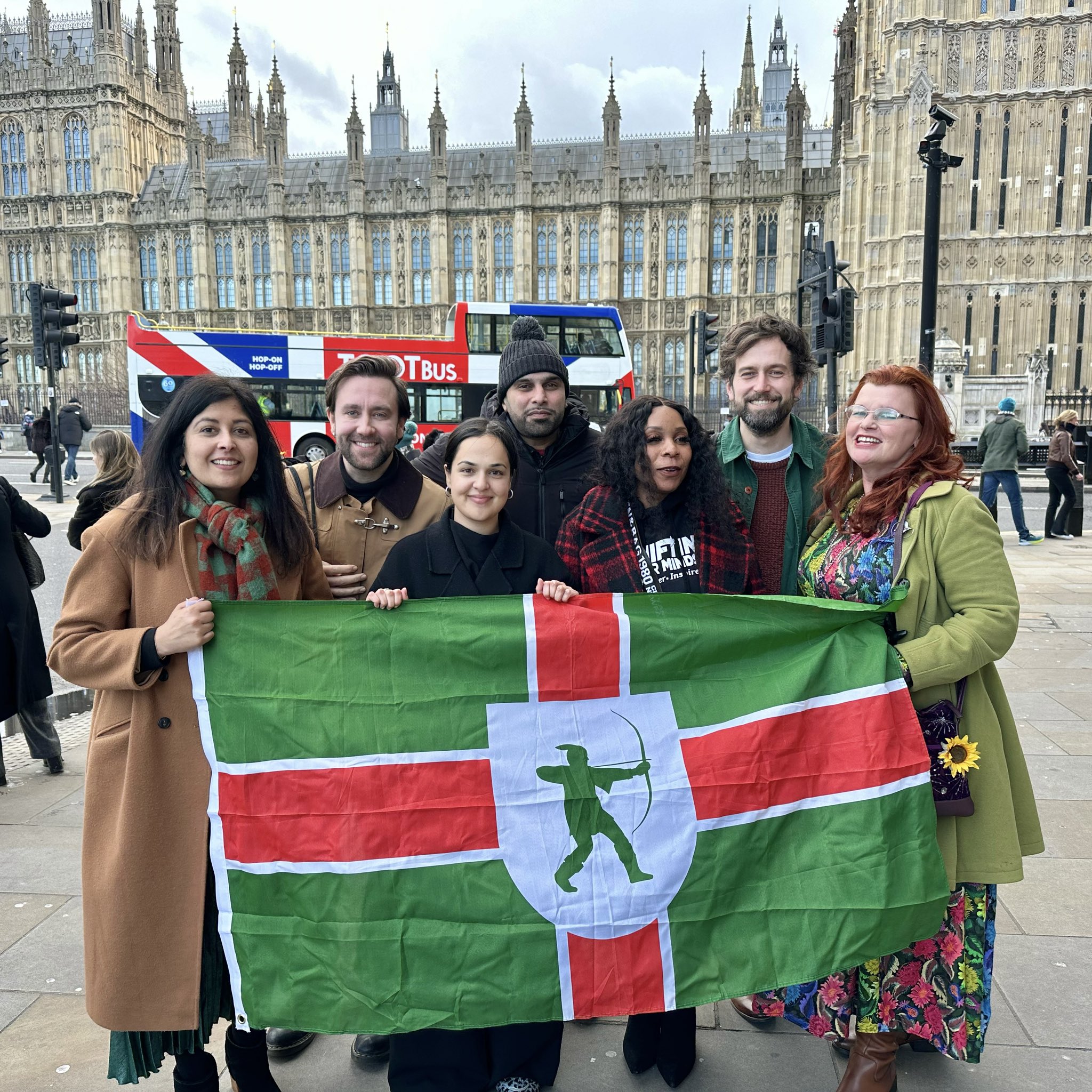 Nadia with Resolve Notts campaigners outside Parliament. They are holding the Nottingham flag.